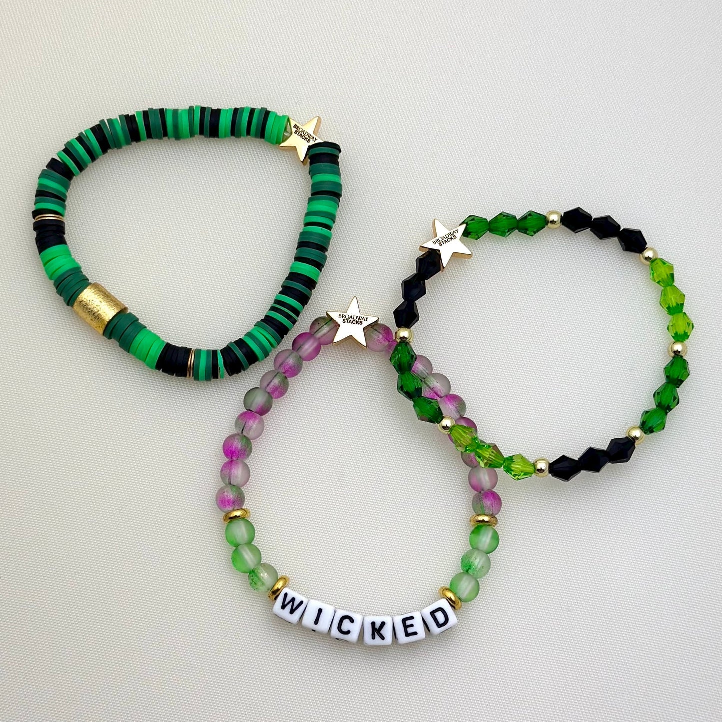 Broadway Stacks WITCH collection. 3 stretch bracelets included in Stack. Greens, white, pinks, gold and black colored beads. Letter beads that spell show quotes. Broadway Stacks gold star logo bead on back.