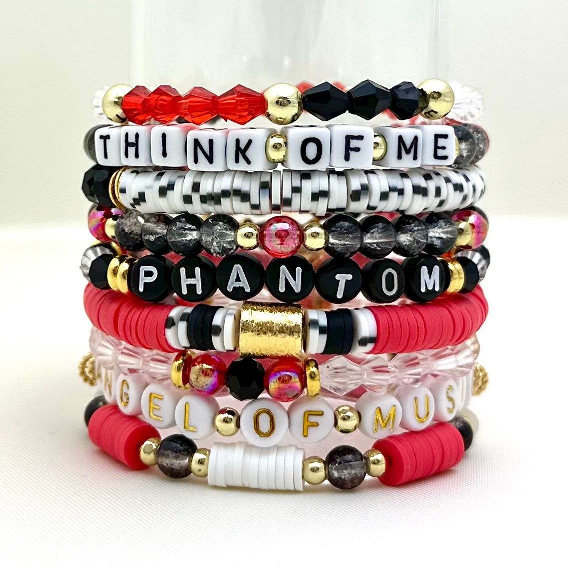 Broadway Stacks Phantom collection. 3 stretch bracelets included in Stack. Red, black, white and gold colored beads. Letter beads that spell Think Of Me.