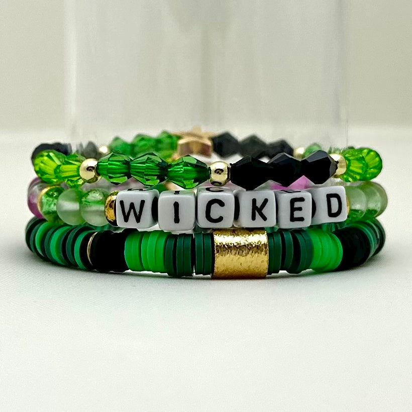 Broadway Stacks WITCH collection. 3 stretch bracelets included in Stack. Greens, white, pinks, gold and black colored beads. Letter beads that spell show quotes. Broadway Stacks gold star logo bead on back.