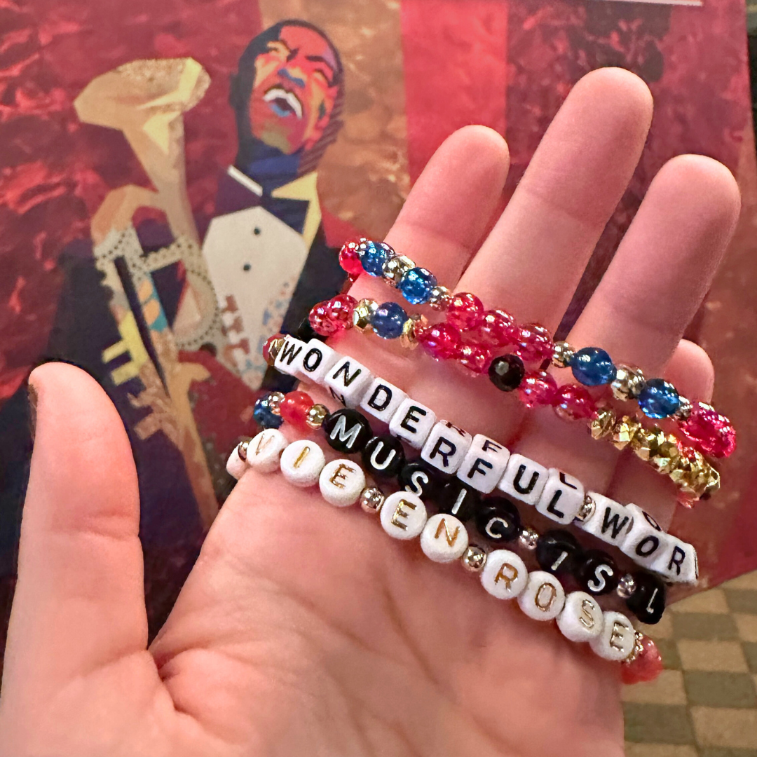 Broadway Stacks JAZZY Collection. 5 stretch bracelets included in Stack. Red, blue, black and gold colored beads. Letter beads that spell quotes. Gold star logo bead to remind you that you shine.