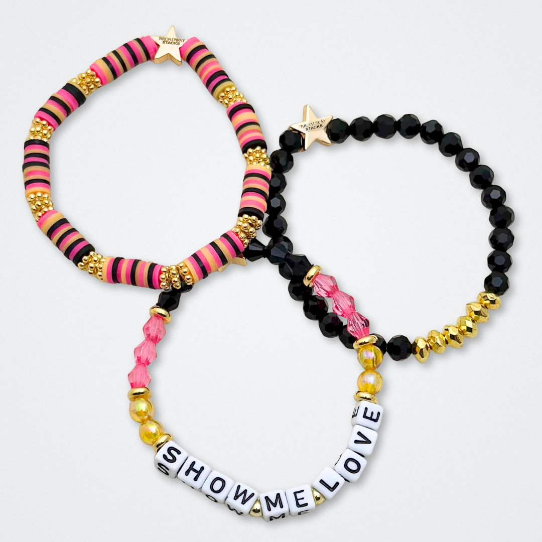 Broadway Stacks De Bois Band collection. 3 stretch bracelets included in Stack. Pinks, golds and black colored beads. Letter beads that spell quotes. Broadway Stacks gold star logo bead to remind you that you shine. & Juliet fans.