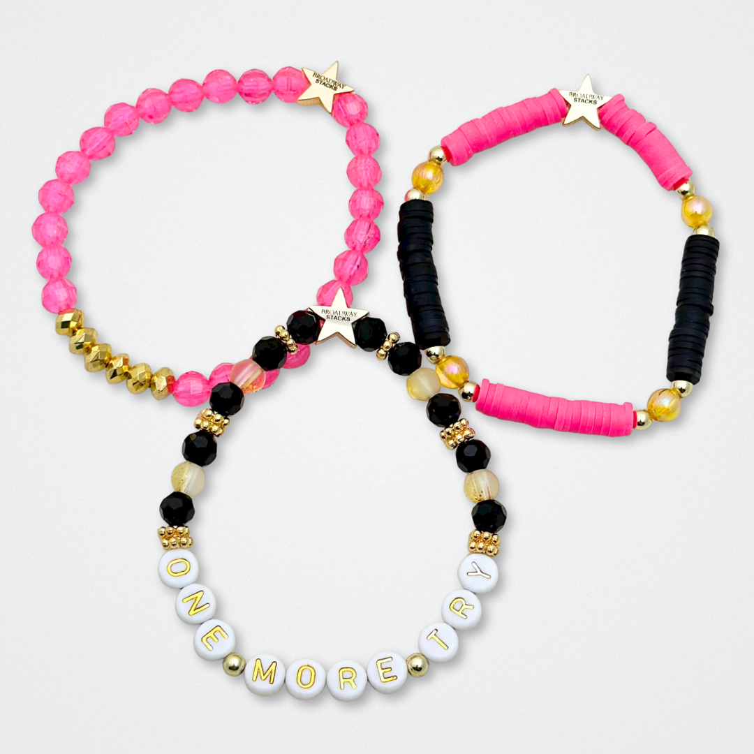 Broadway Stacks De Bois Band collection. 3 stretch bracelets included in Stack. Pinks, golds and black colored beads. Letter beads that spell quotes. Broadway Stacks gold star logo bead to remind you that you shine. & Juliet fans.