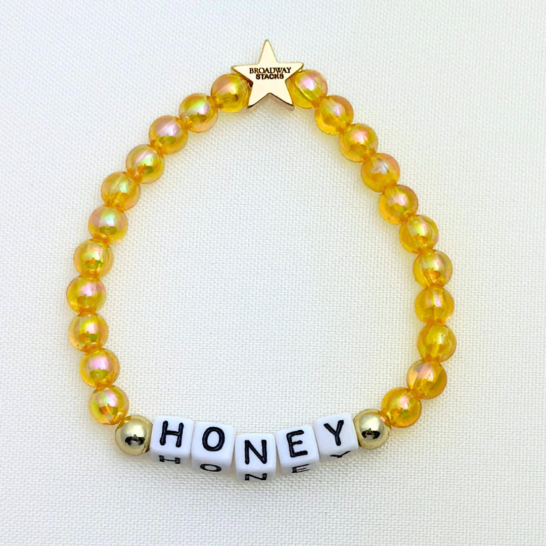 Broadway Stacks HONEY Collection. 3 stretch bracelets included in Stack. Red, yellow and gold colored beads. Letter beads that spell quotes. Gold star logo bead to remind you that you shine.