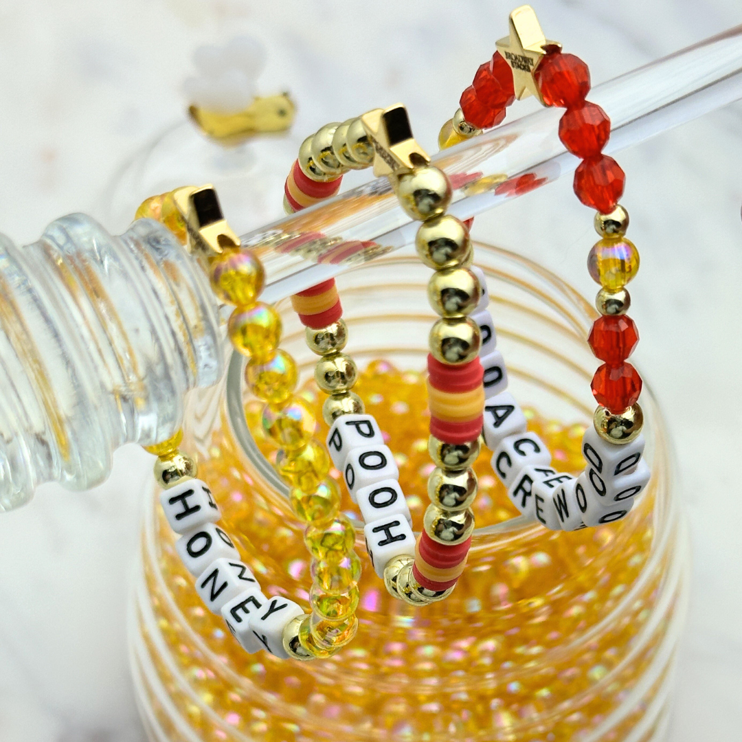 Broadway Stacks HONEY Collection. 3 stretch bracelets included in Stack. Red, yellow and gold colored beads. Letter beads that spell quotes. Gold star logo bead to remind you that you shine.