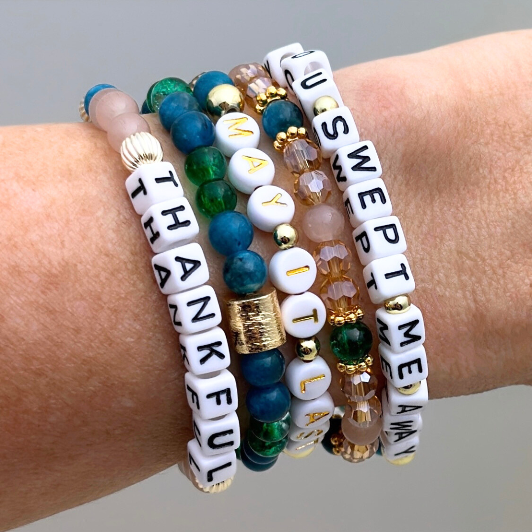 Broadway Stacks SAILOR Collection. 5 stretch bracelets included in Stack. Teal, green, blue and gold colored beads. Letter beads that spell quotes. Gold star logo bead to remind you that you shine.