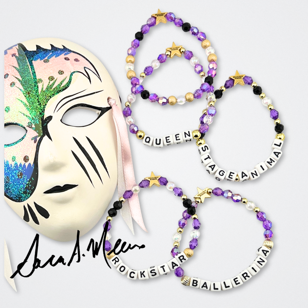 Broadway Stacks Special Edition Sara Mearns ROCKSTAR Bracelet Collection. 5 stretch bracelets included in Stack. Purple, clear, white, black and gold colored beads. Letter beads that spell quotes. Gold star logo bead to remind you that you shine. Sara Mearns and Ballet fans.