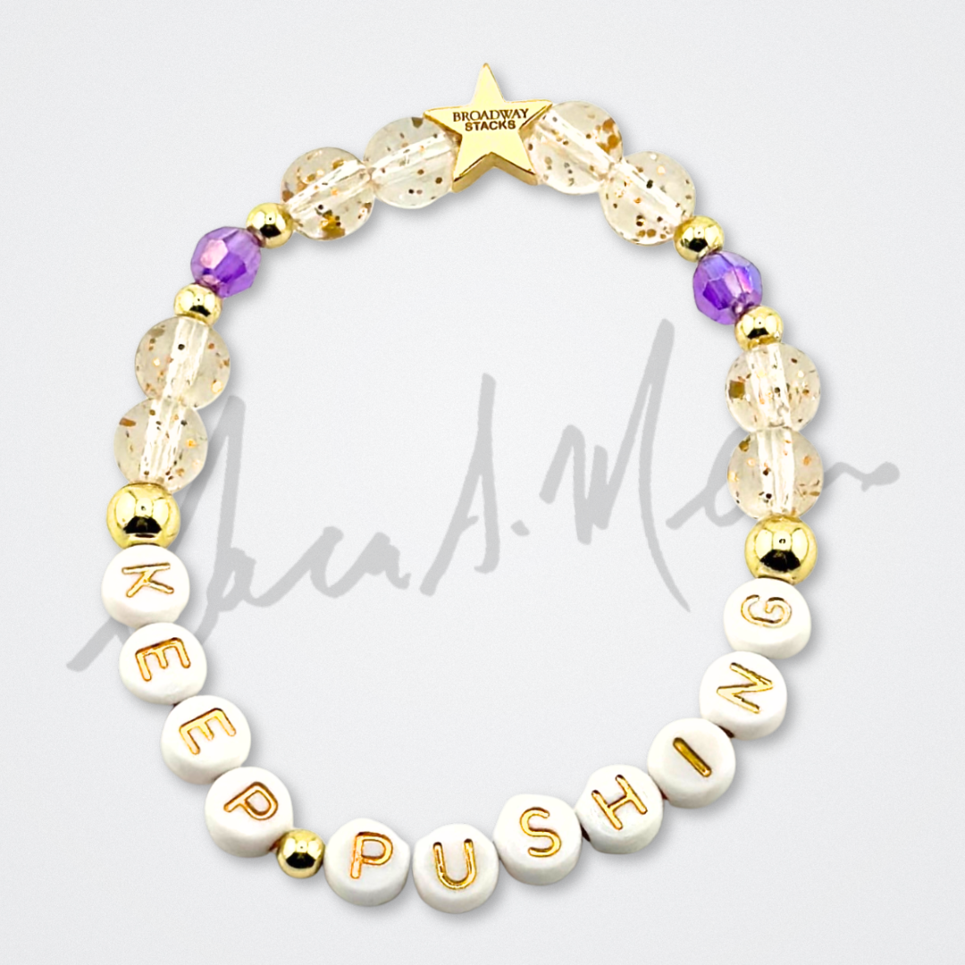 Broadway Stacks Special Edition Sara Mearns STAGE Bracelet Collection. 5 stretch bracelets included in Stack. Purple, pink, clear, white, glitter and gold colored beads. Letter beads that spell quotes. Gold star logo bead to remind you that you shine. Sara Mearns NYCB Principal Dancer and Ballet fans.