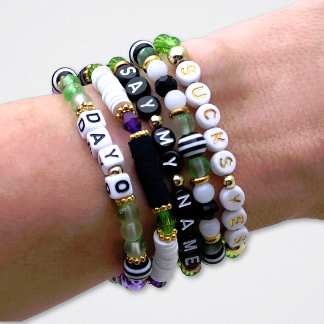 Broadway Stacks NETHERWORLD Collection. 5 stretch bracelets included in Stack. Green, black, purple, striped and gold colored beads. Letter beads that spell quotes. Gold star logo bead to remind you that You Shine. Beetlejuice fans.