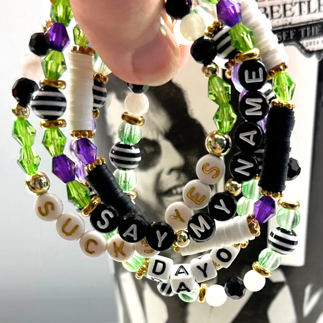 Broadway Stacks NETHERWORLD Collection. 5 stretch bracelets included in Stack. Green, black, purple, striped and gold colored beads. Letter beads that spell quotes. Gold star logo bead to remind you that You Shine. Beetlejuice fans.