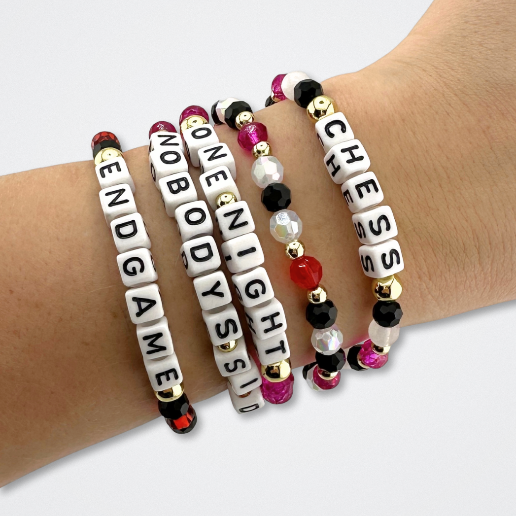 Broadway Stacks CHECKMATE Collection. 5 stretch bracelets included in Stack. Black, white, red, pink and gold colored beads. Letter beads that spell quotes. Star logo bead to remind you that you shine. Chess the Musical fans.