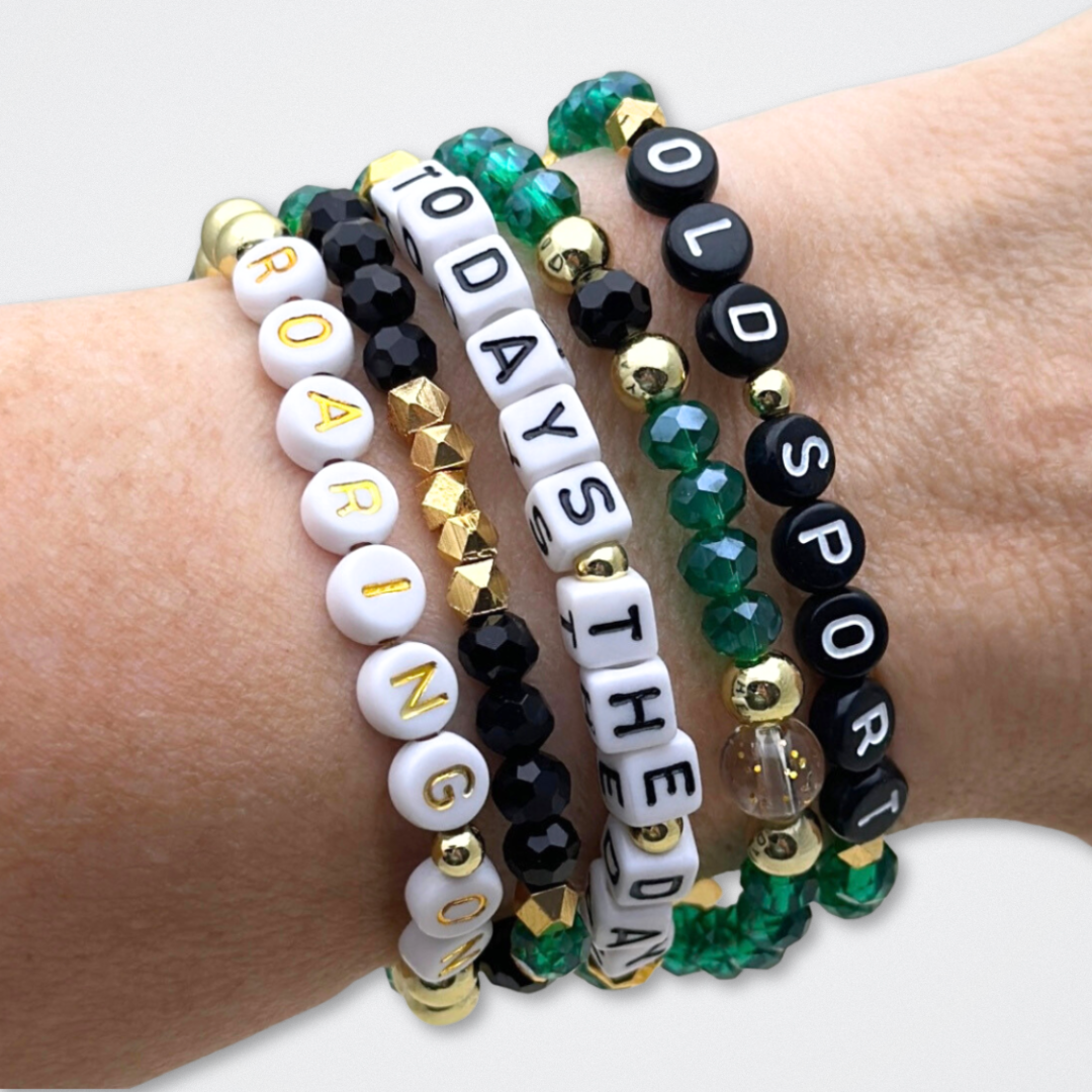 Broadway Stacks NEW MONEY Collection. 5 stretch bracelets included in Stack. Teal, green, black and gold colored beads. Letter beads that spell quotes. Gold star logo bead to remind you that You Shine. Great Gatsby fans.