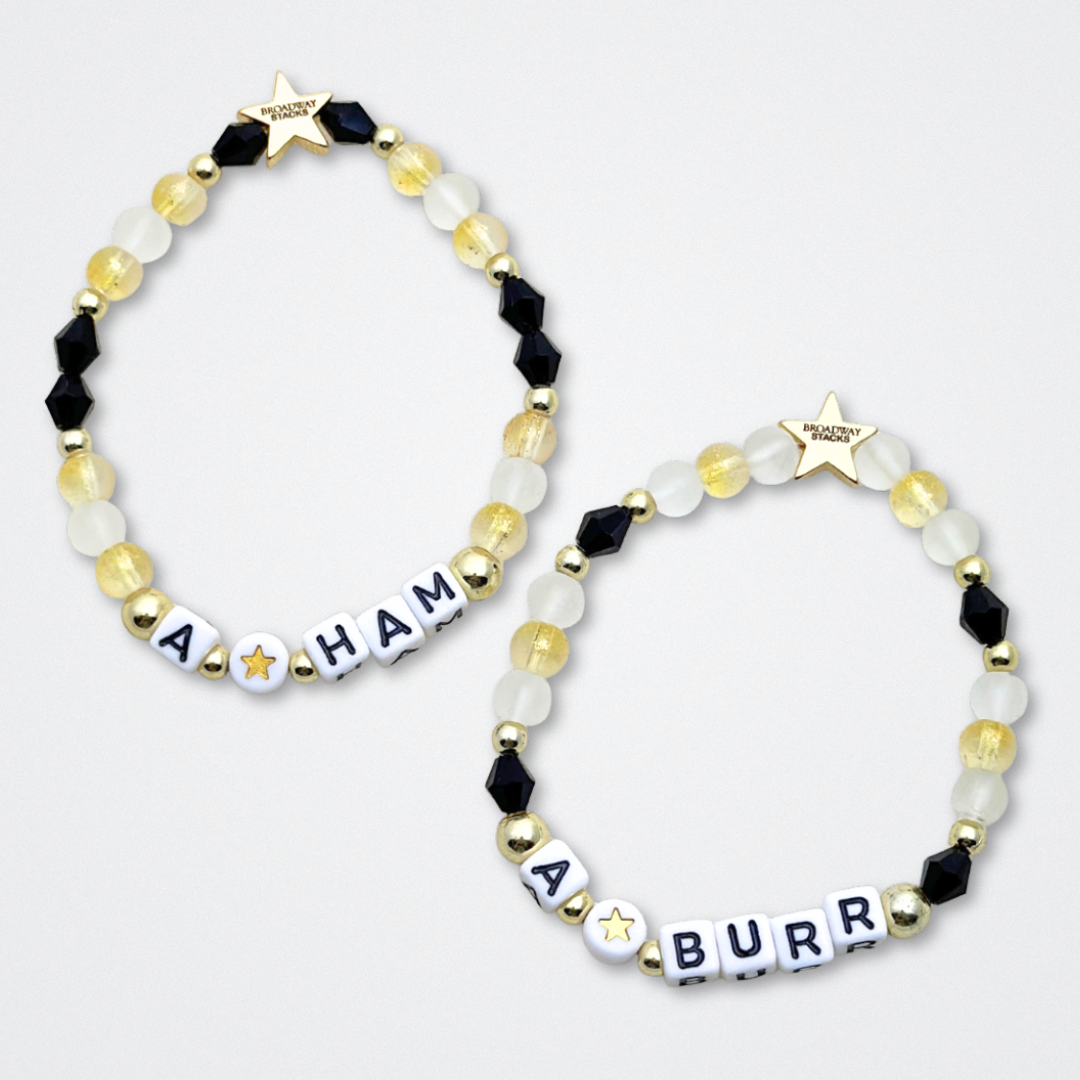 Broadway Stacks REVOLUTION Collection. 5 stretch bracelets included in Stack. Yellow, white, black and gold colored beads. Letter beads that spell quotes. Gold star logo bead to remind you that You Shine. Hamilton the Musical fans.
