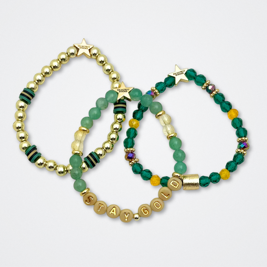 Broadway Stacks STAY GOLD collection. Stretch bracelets included in Stack. Gold, yellow, green and grey colored beads. Letter beads that have show quote or name. Broadway Stacks gold star logo bead to remind you that You Shine. The Outsiders the Musical fans.