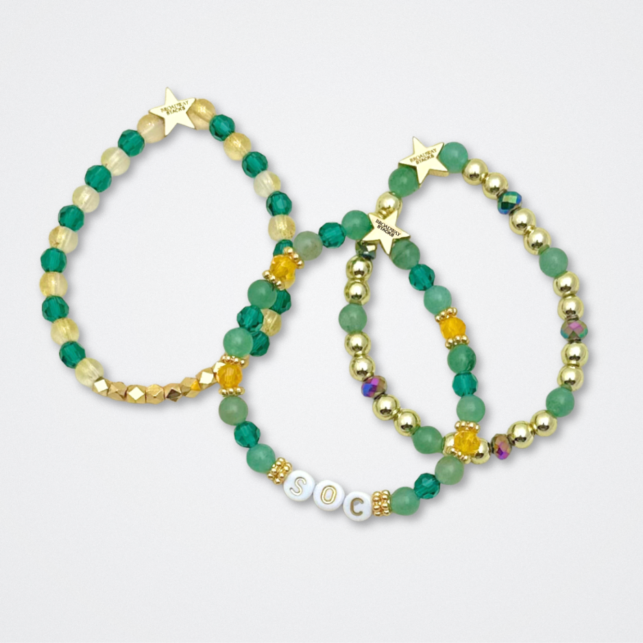 Broadway Stacks STAY GOLD collection. Stretch bracelets included in Stack. Gold, yellow, green and grey colored beads. Letter beads that have show quote or name. Broadway Stacks gold star logo bead to remind you that You Shine. The Outsiders the Musical fans.