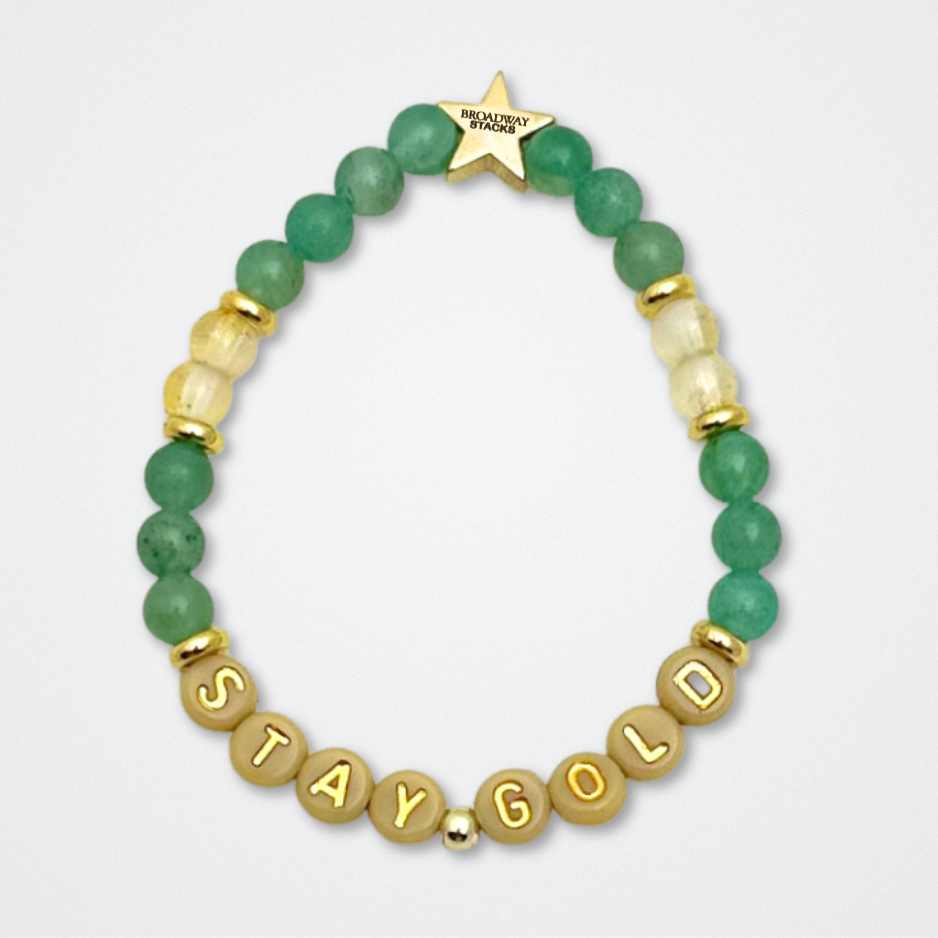 Broadway Stacks STAY GOLD collection. Stretch bracelets included in Stack. Gold, yellow, green and grey colored beads. Letter beads that have show quote or name. Broadway Stacks gold star logo bead to remind you that You Shine. The Outsiders the Musical fans.