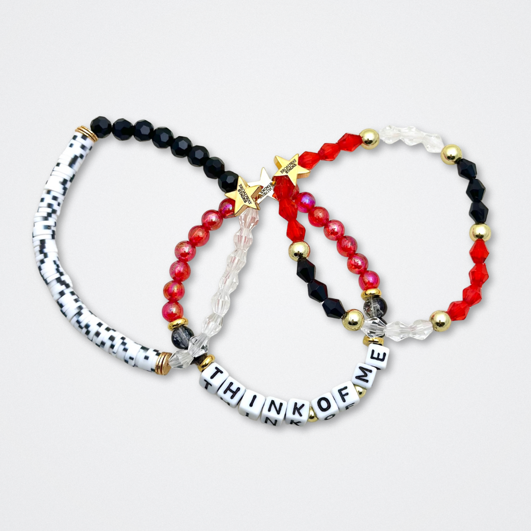 Broadway Stacks MASK collection. Bead bracelets included in Stack. Red, black, white and gold colored beads. Letter beads that spell quotes. Team Phantom, Team Christine, Team Raoul. Gold star logo bead to remind you that You Shine. Phantom of the Opera and Masquerade fans.