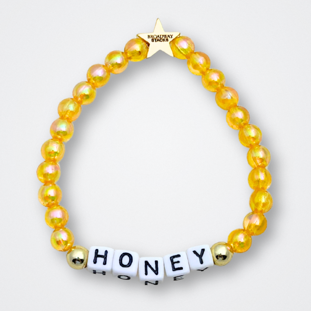 Broadway Stacks HONEY Collection. 3 stretch bracelets included in Stack. Red, yellow and gold colored beads. Letter beads that spell quotes. Gold star logo bead to remind you that You Shine. Winnie the Pooh fans.