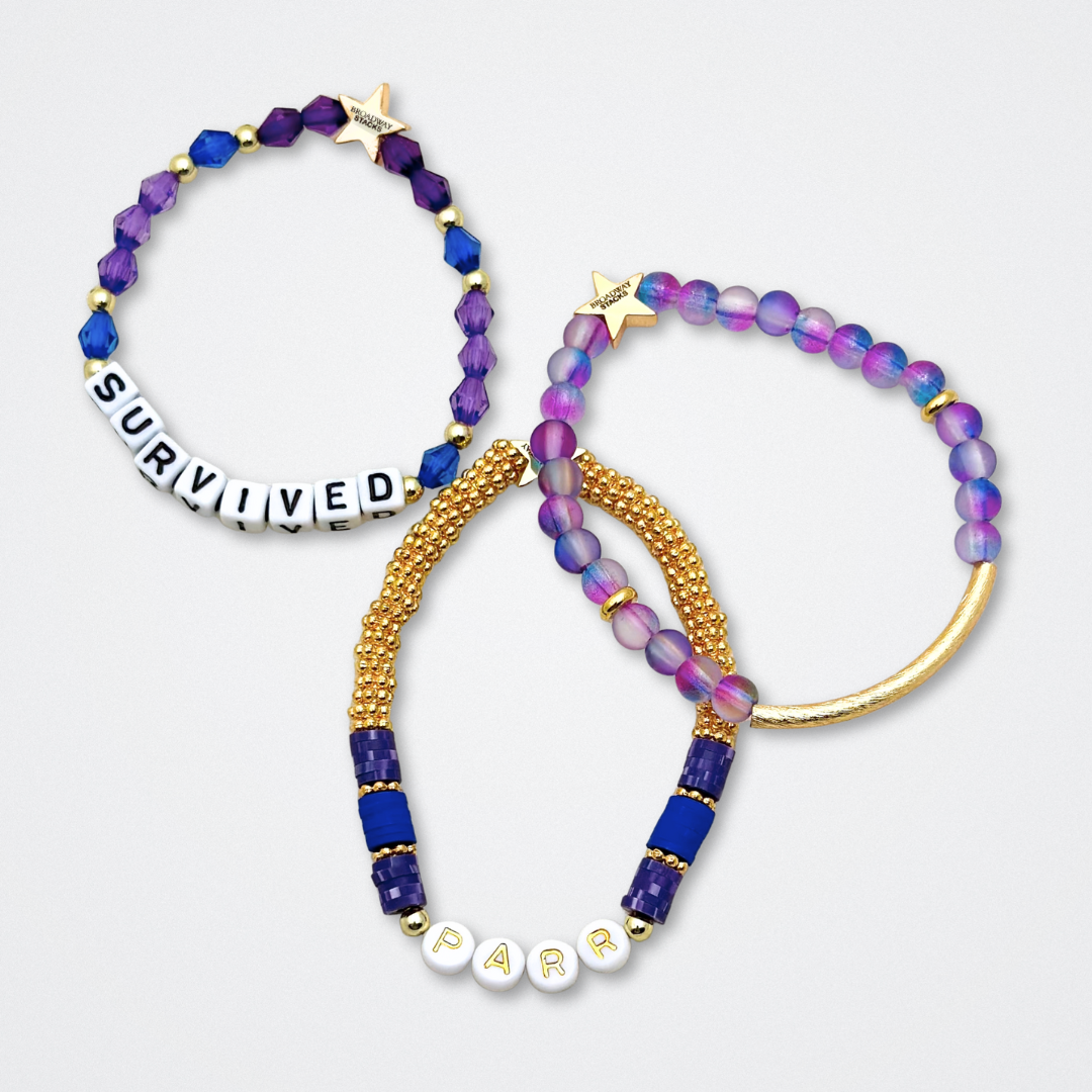 Broadway Stacks QUEEN collection. Stretch bracelets included in Stack. Gold, yellow, green, white, red, pink and blue colored beads. Letter beads that spell each queen. Also Herstory collection. Broadway Stacks gold star logo bead to remind you that You Shine. SIX the Musical fans.