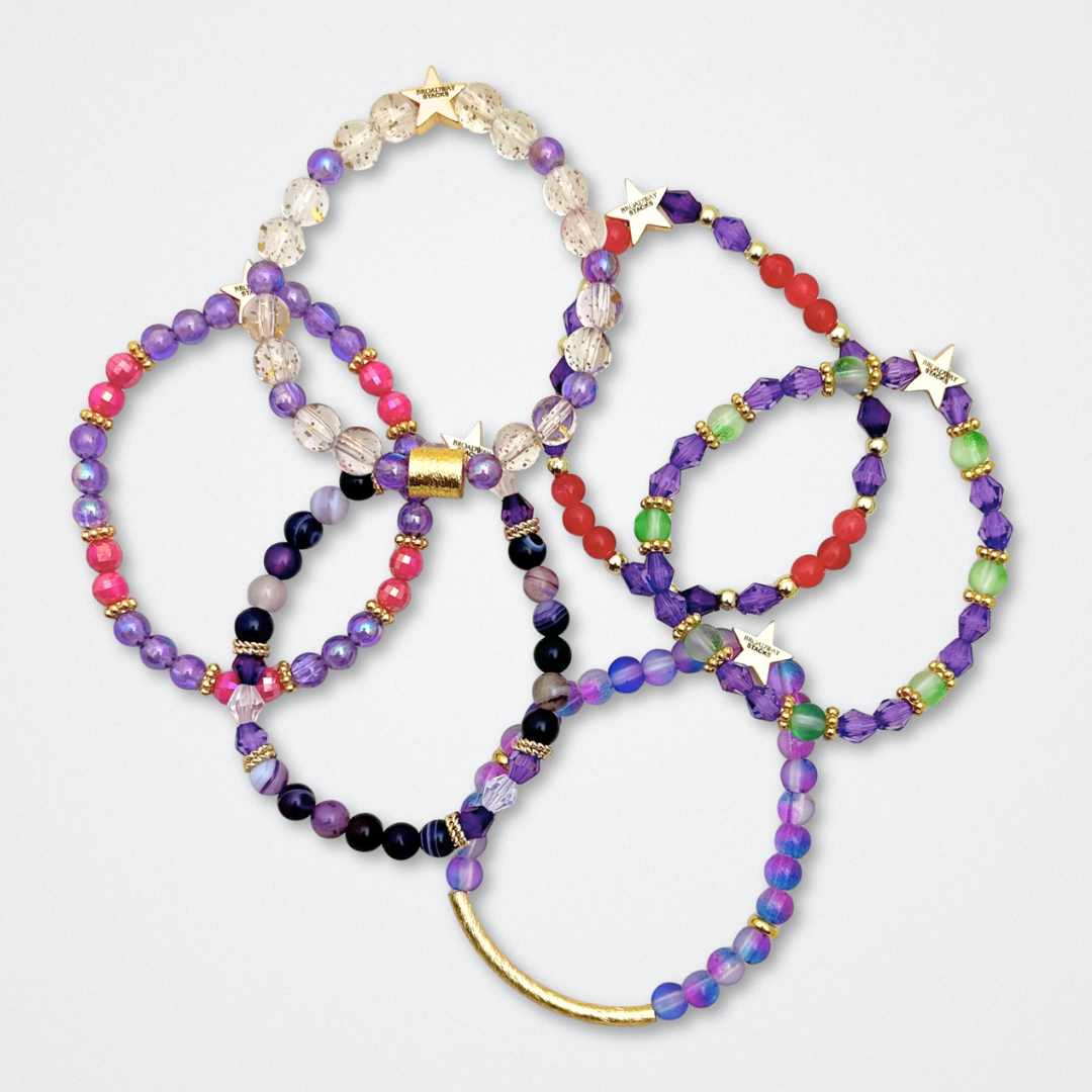 Broadway Stacks QUEEN collection. Stretch bracelets included in Stack. Gold, yellow, green, white, red, pink and blue colored beads. Letter beads that spell each queen. Also Herstory collection. Broadway Stacks gold star logo bead to remind you that You Shine. SIX the Musical fans.