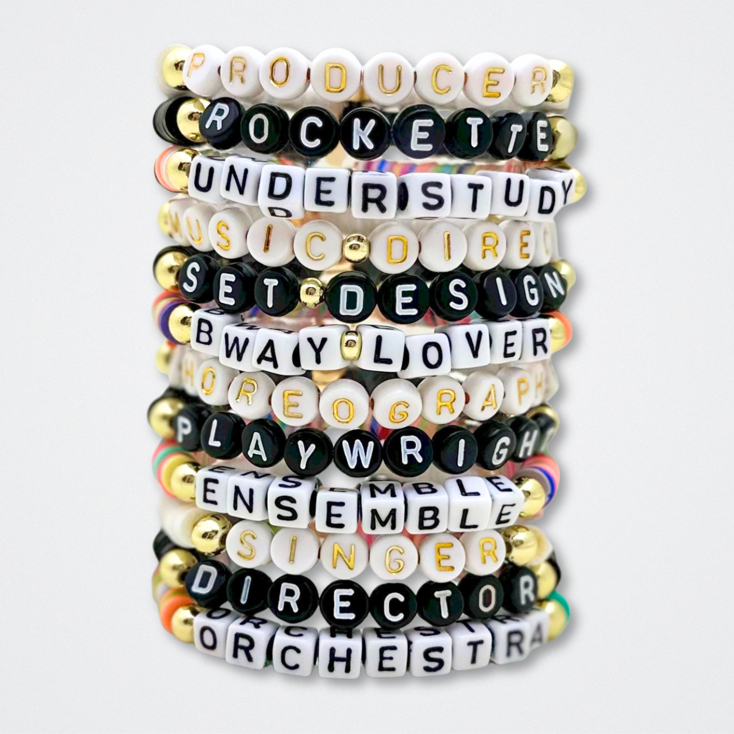 Stack of letter heishi bracelets with various theater roles on a white background. Broadway Stacks theatre-themed Spotlight bracelets highlighting ALL theater roles. Because everyone deserves to shine.