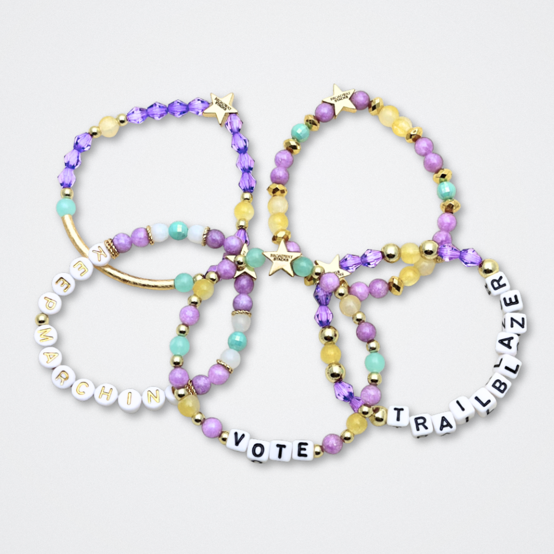 Broadway Stacks CAMPAIGN Collection. 5 stretch bracelets included in Stack. Purple, yellow, teal and gold colored beads. Letter beads that spell quotes. Gold star logo bead to remind you that you shine. Suffs fans.