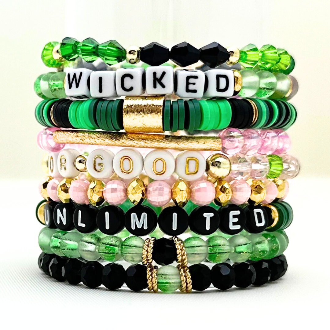 Broadway Stacks Witch collection. 3 stretch bracelets included in Stack. Greens, pinks, black and gold colored beads. Letter beads that spell Wicked. Gold star logo bead on every bracelet.