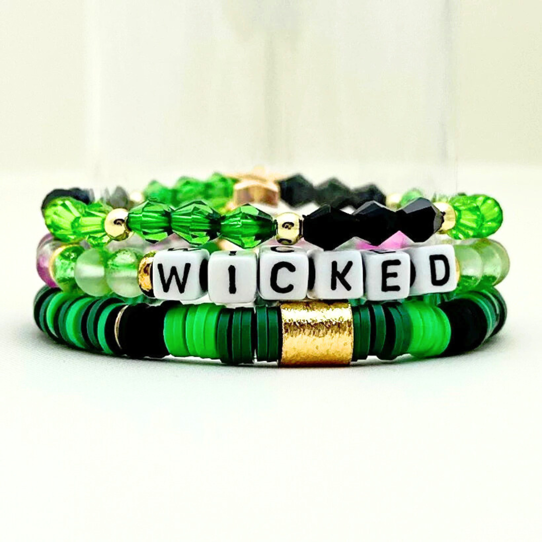 Broadway Stacks Witch collection. 3 stretch bracelets included in Stack. Greens, pinks, black and gold colored beads. Letter beads that spell Wicked. Gold star logo bead on every bracelet.