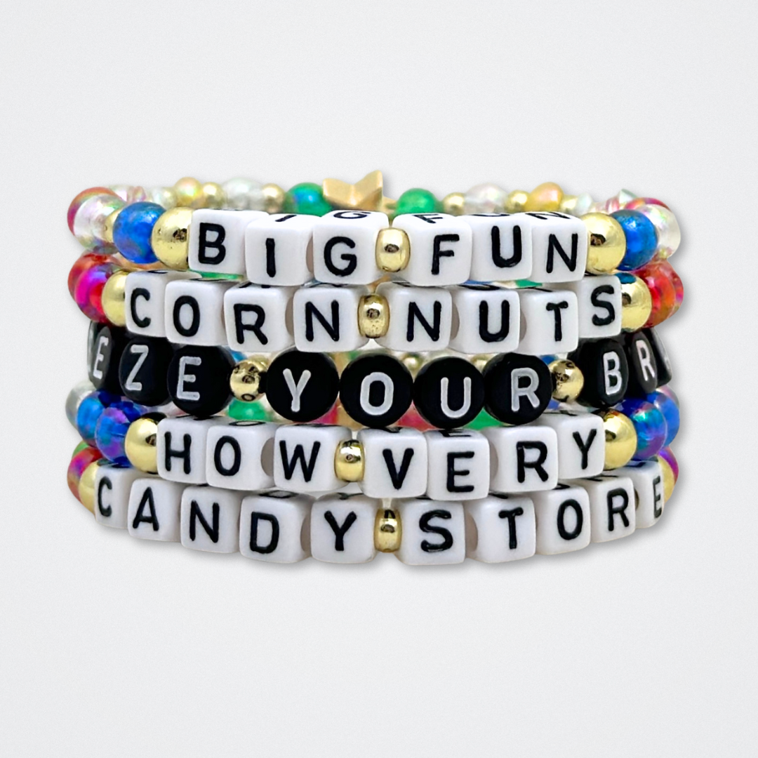 Broadway Stacks CORN NUTS Collection. 5 stretch bracelets included in Stack. Red, yellow, green, blue, black and gold colored beads. Letter beads that spell quotes. Gold star logo bead to remind you that you shine. Heathers the Musical fans.