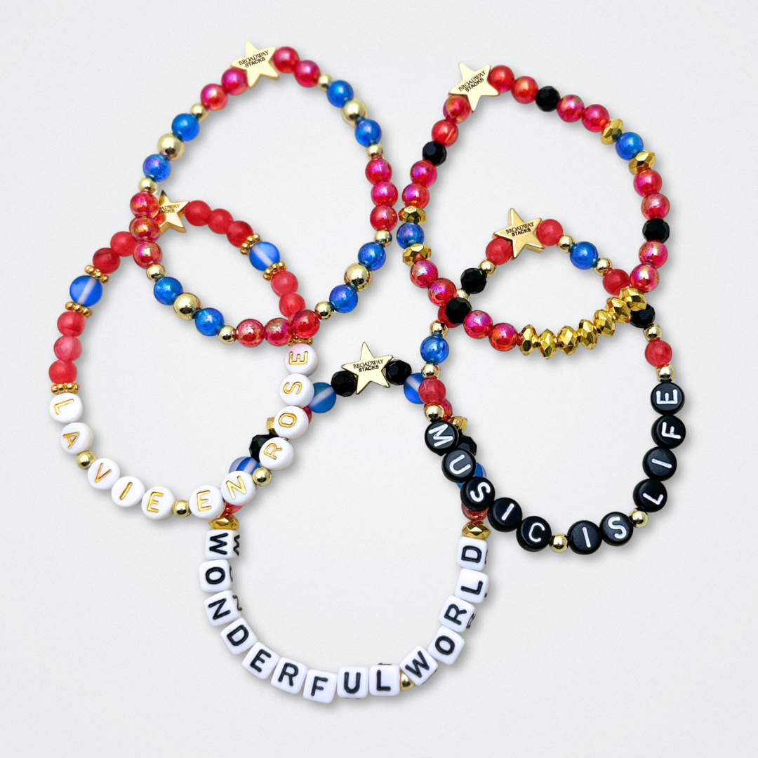Broadway Stacks JAZZY Collection. 5 stretch bracelets included in Stack. Red, blue, black and gold colored beads. Letter beads that spell quotes. Gold star logo bead to remind you that you shine. Wonderful World musical and Louis Armstrong fans.