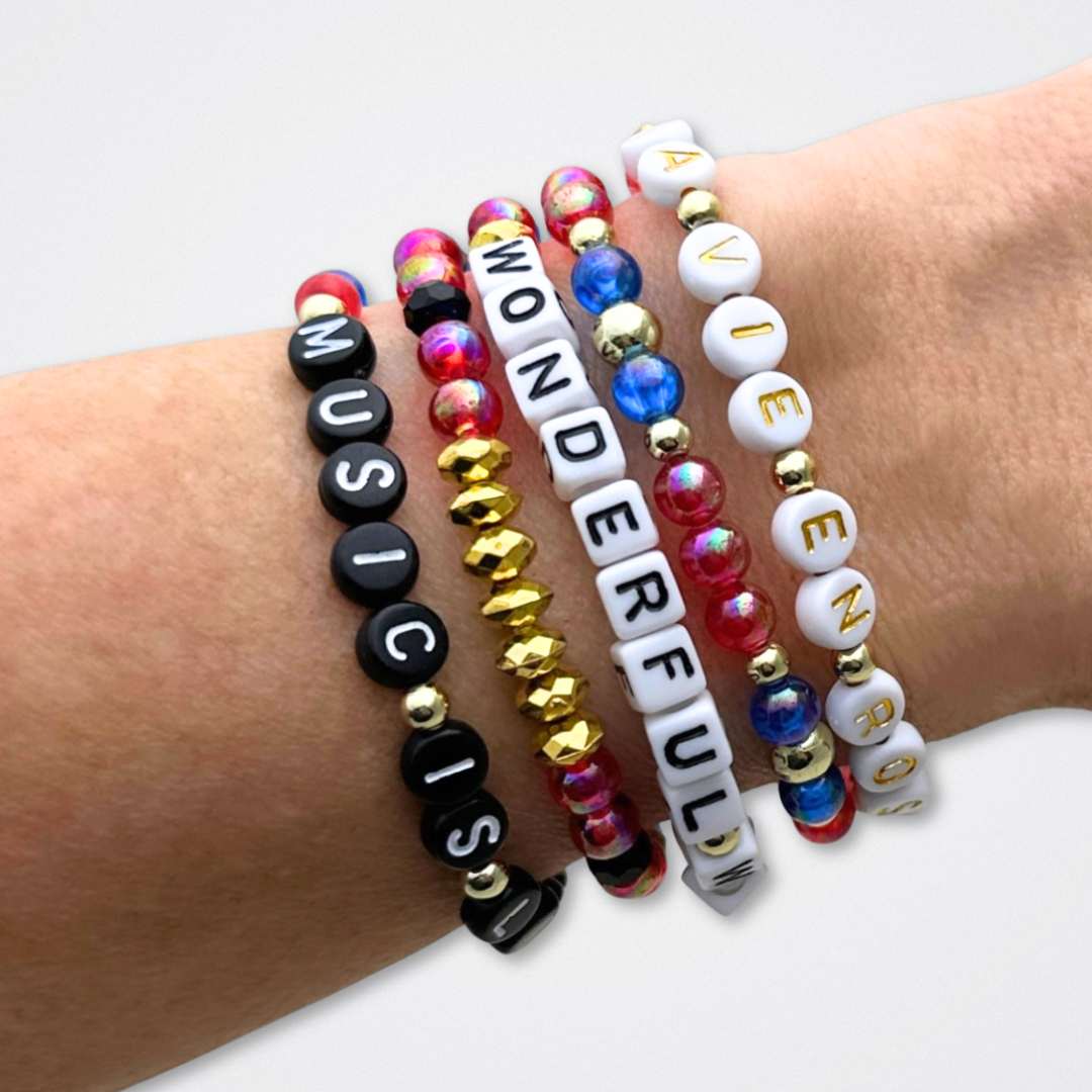 Broadway Stacks JAZZY Collection. 5 stretch bracelets included in Stack. Red, blue, black and gold colored beads. Letter beads that spell quotes. Gold star logo bead to remind you that you shine. Wonderful World musical and Louis Armstrong fans.