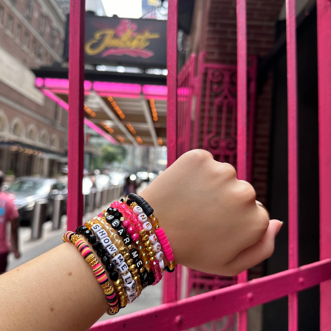 Broadway Stacks De Bois Band collection. 9 stretch bracelets included in Stack. Pinks, golds and black colored beads. Letter beads that spell quotes. Broadway Stacks gold star logo bead to remind you that you shine. & Juliet fans.