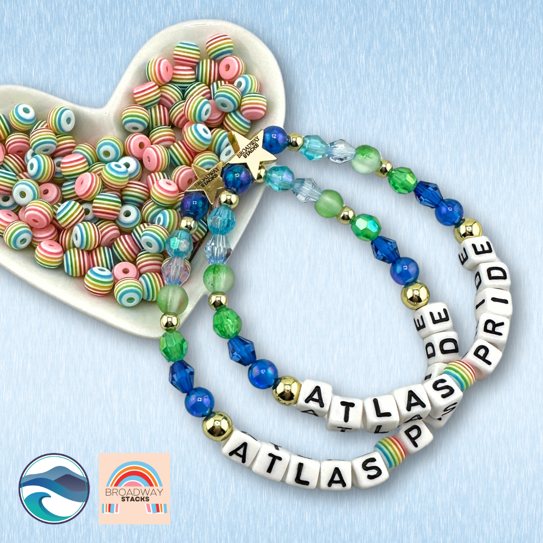 Broadway Stacks x Atlas Pride Limited Edition bracelet in blues, greens and rainbow beads on a blue background.