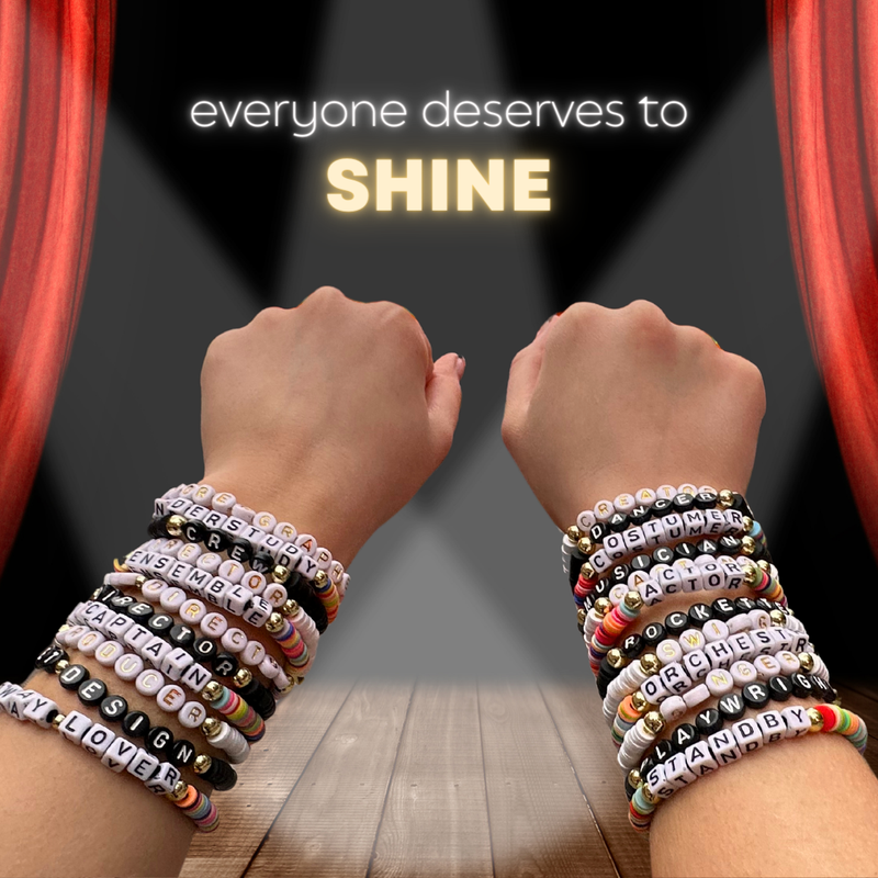 Broadway Stacks theatre-themed bracelets SPOTLIGHT Collection. Letter beads spell theatre roles like ENSEMBLE, ACTOR and STANDBY with multicolored and gold-colored beads on a stage background. Because everyone shines like a star.