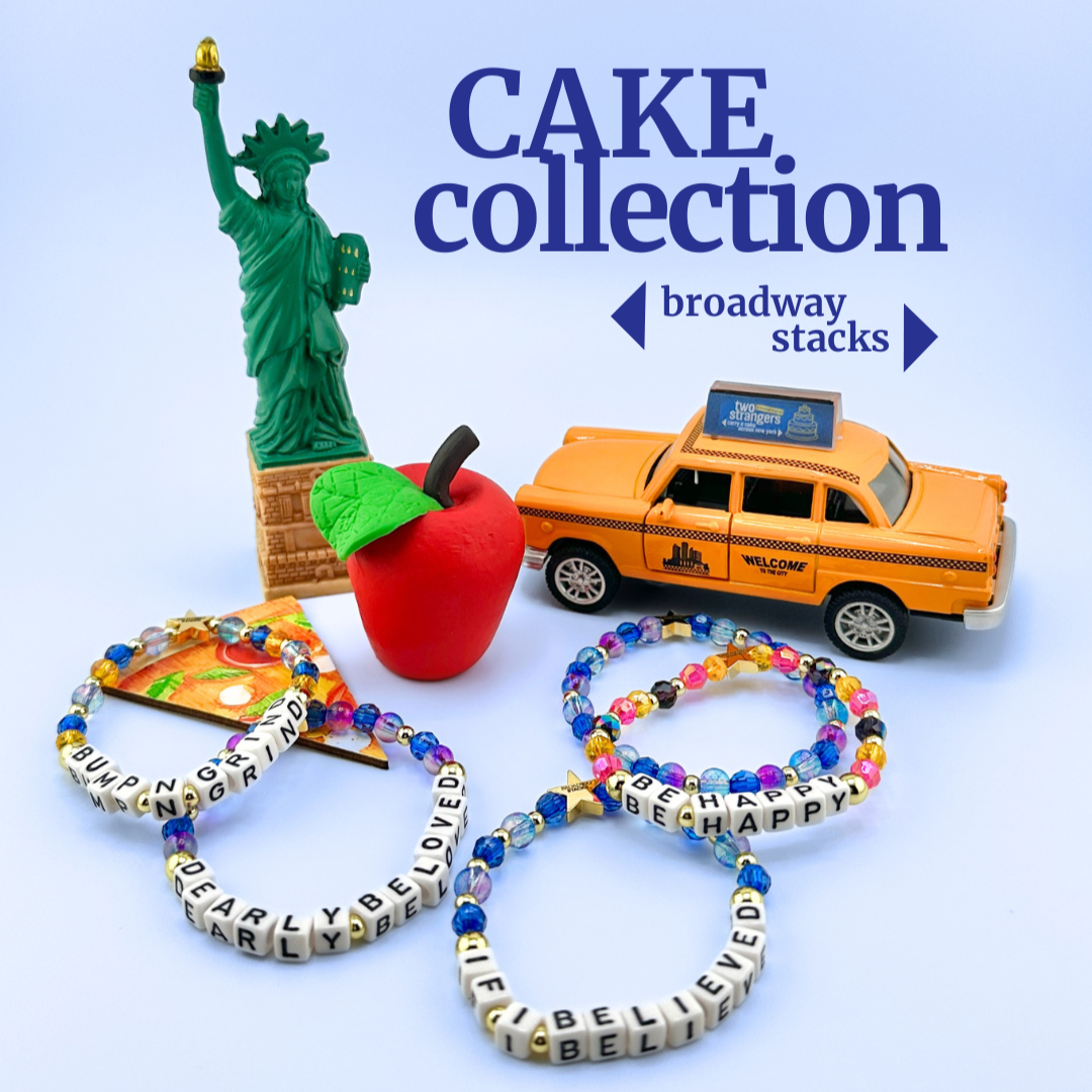 Broadway Stacks CAKE Collection bead bracelets on blue background with mini taxi, apple and Statue of Liberty