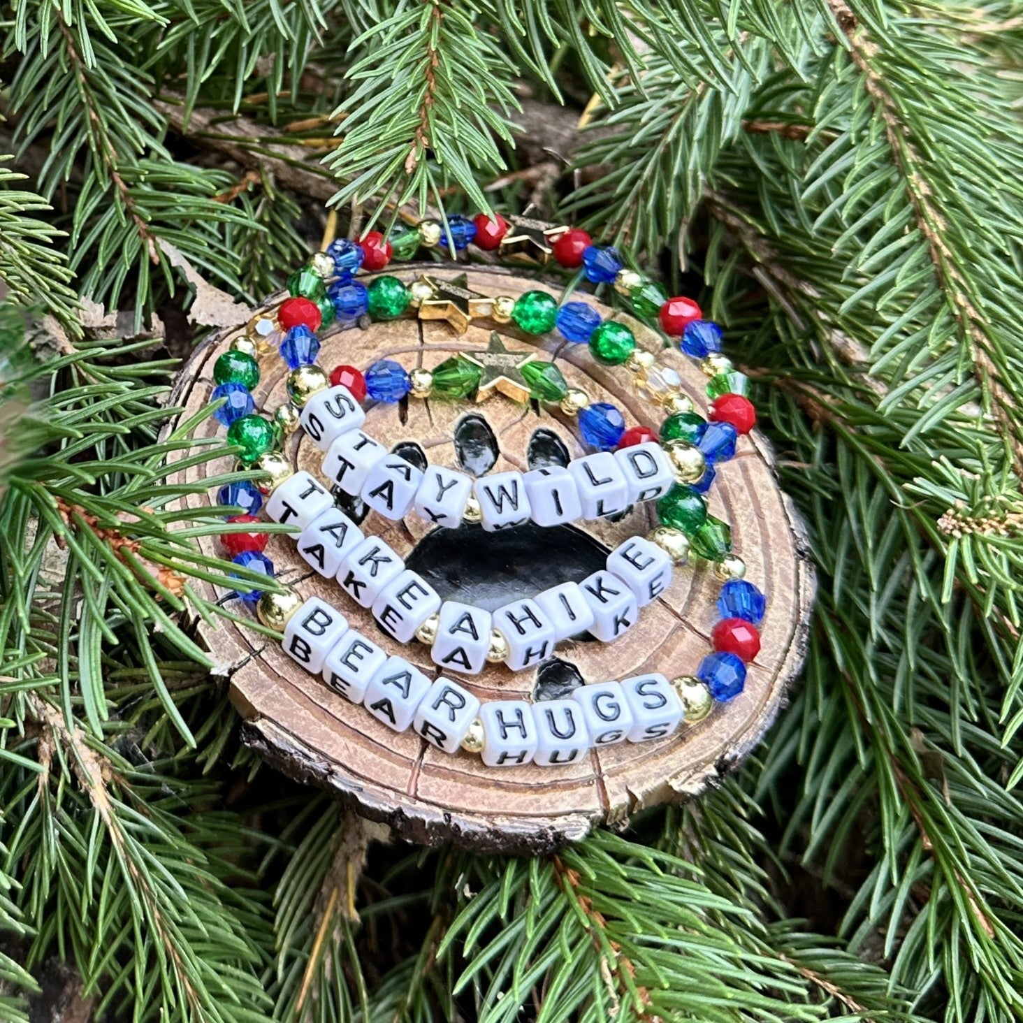 Broadway Stacks MOUNTAIN Collection of Bead bracelets. Dark red, blue and green bracelets on a tree with bear paw decor.