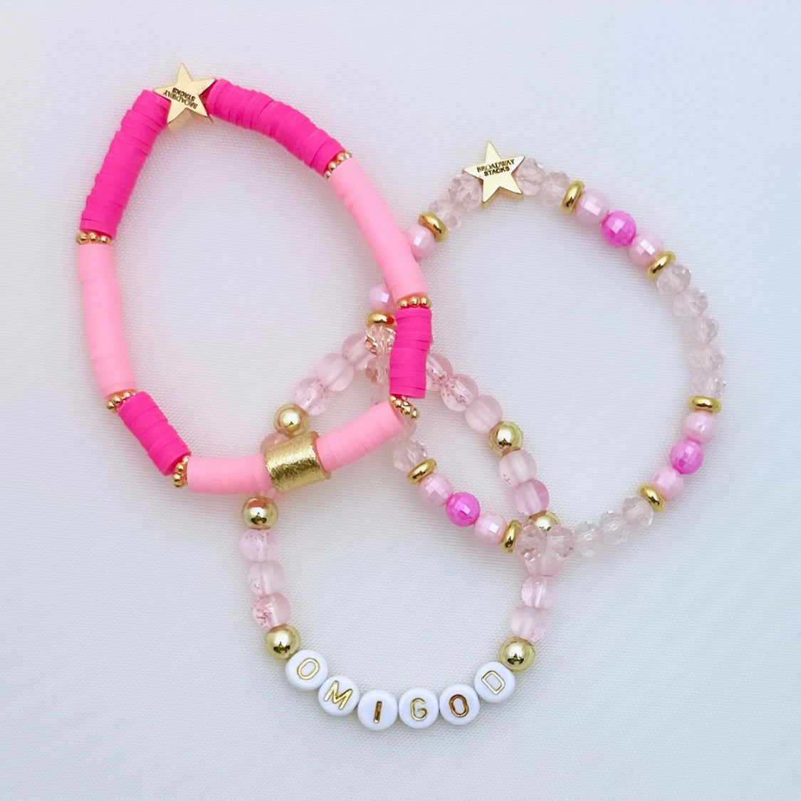 Broadway Stacks Omigod collection. 3 stretch bracelets included in Stack. Pinks, white and gold colored beads. Letter beads that spell Omigod.