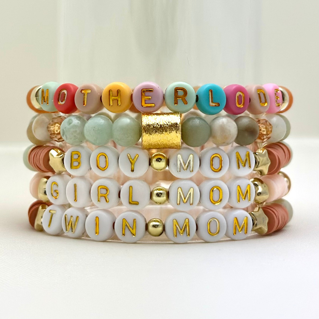 Broadway Stacks Motherlode Special Edition bracelets. Stretch bracelets. Greens, browns, white and gold colored beads. Letter beads that spell Motherlode, Boy Mom, Girl Mom, Twin Mom,