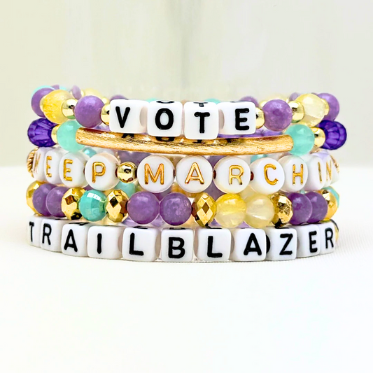 Broadway Stacks CAMPAIGN Collection. 5 stretch bracelets included in Stack. Purple, yellow, teal and gold colored beads. Letter beads that spell quotes. Gold star logo bead to remind you that you shine. Suffs fans. 