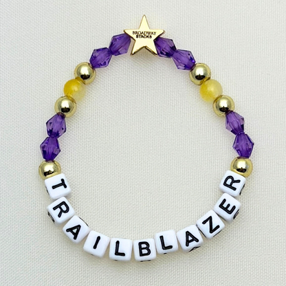 Suffs musical TRAILBLAZER bead bracelet, purple, yellow, teal and gold beads, gold star logo bead of Broadway Stacks