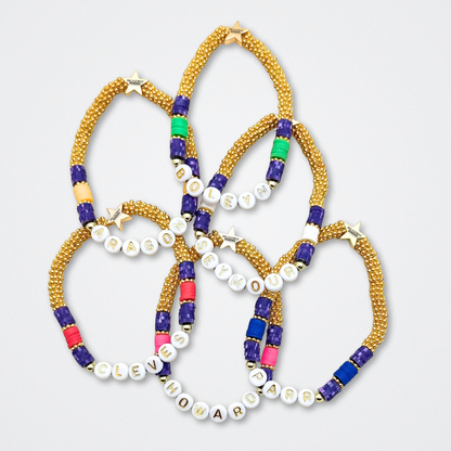 Broadway Stacks QUEEN collection. Stretch bracelets included in Stack. Gold, yellow, green, white, red, pink and blue colored beads. Letter beads that spell each queen. Also Herstory collection. Broadway Stacks gold star logo bead to remind you that You Shine. SIX the Musical fans.