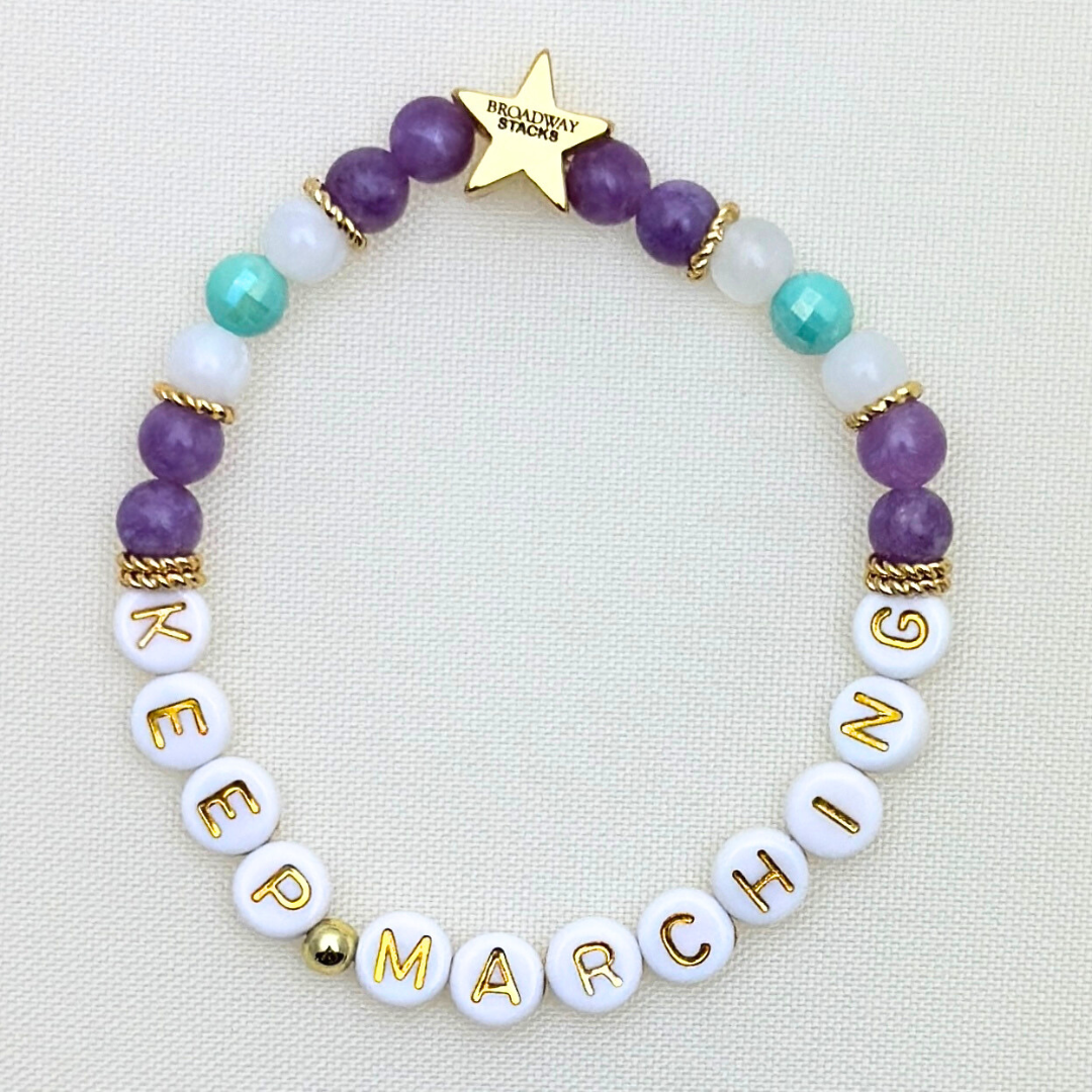 Suffs musical KEEP MARCHING bead bracelet, purple, yellow, teal and gold beads, gold star logo bead of Broadway Stacks