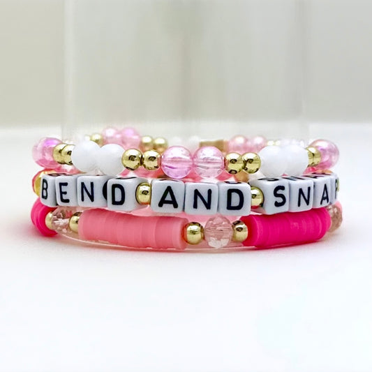 Broadway Stacks Bend and Snap collection. 3 stretch bracelets included in Stack. Pinks, white and gold colored beads. Letter beads that spell Bend and Snap.