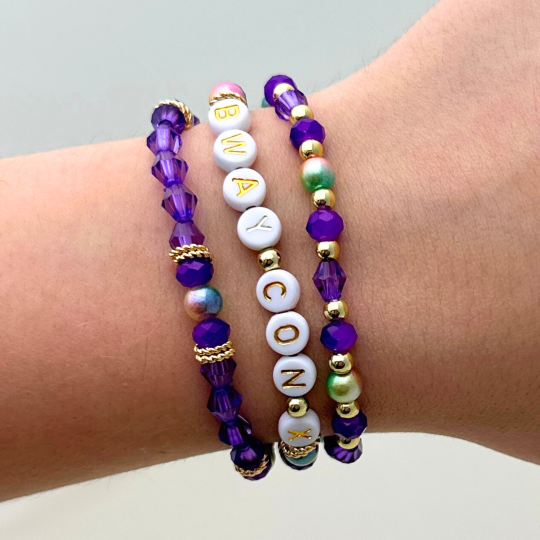 Broadway Stacks BroadwayCon X 2025 Special Edition bracelet. Stack of 3 bracelets. Purple, gold and iridescent colored beads. Letter beads that spell Bway Con X.