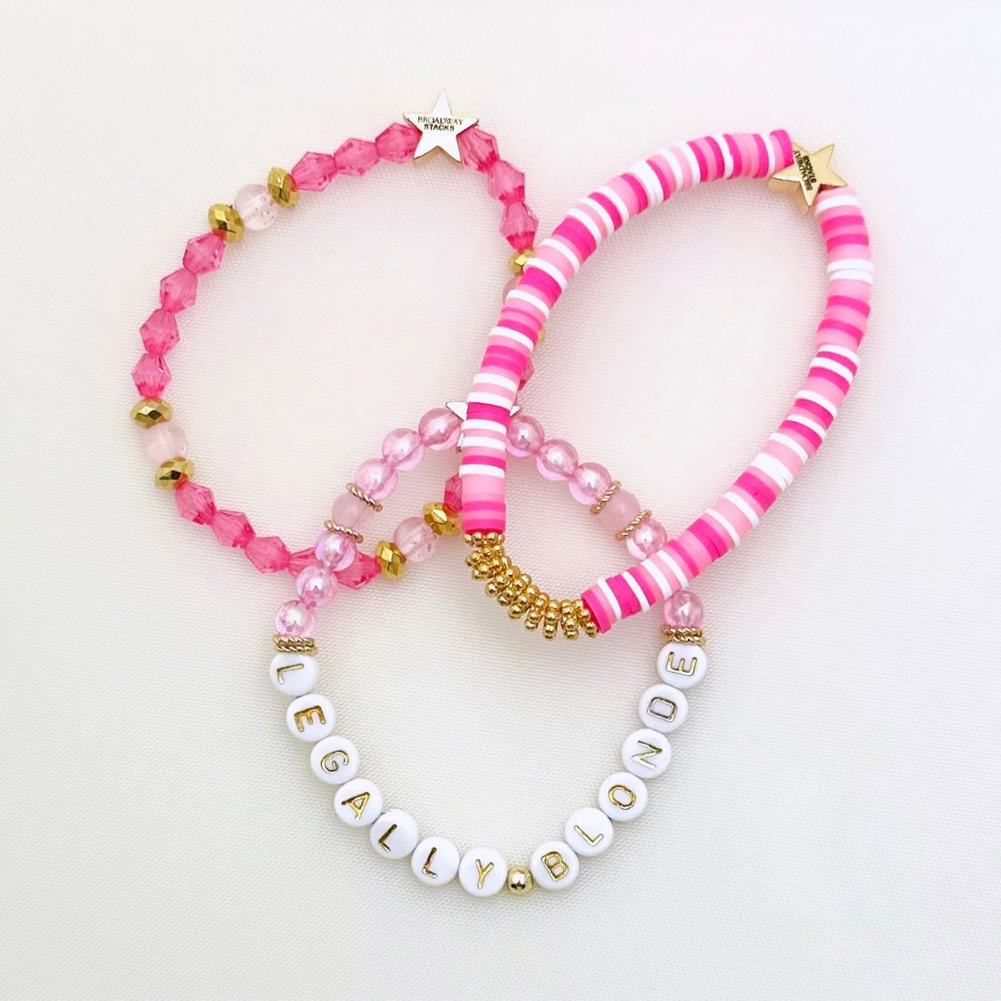 Broadway Stacks Legally Blonde collection. 3 stretch bracelets included in Stack. Pinks, white and gold colored beads. Letter beads that spell Legally Blonde.