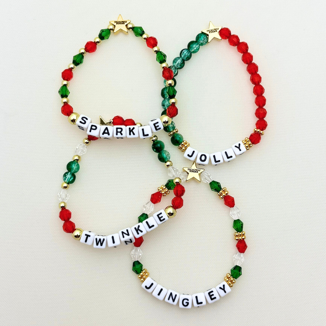 Broadway Stacks CHRISTMAS Collection. 4 stretch bracelets included in Stack. Red, green, white and gold colored beads. Letter beads that spell quotes. Gold star logo bead to remind you that you shine.