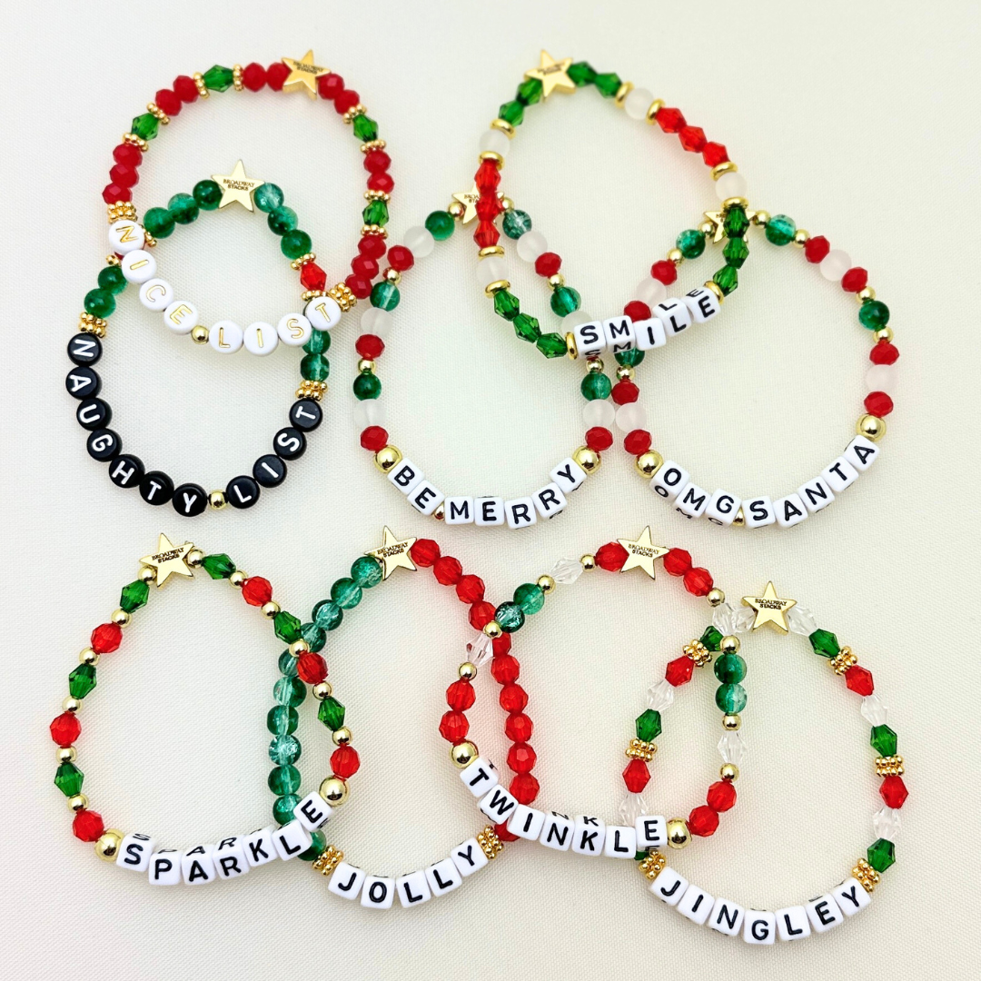 Broadway Stacks CHRISTMAS Collection. 9 stretch bracelets included in Stack. Red, green, white and gold colored beads. Letter beads that spell quotes. Gold star logo bead to remind you that you shine.