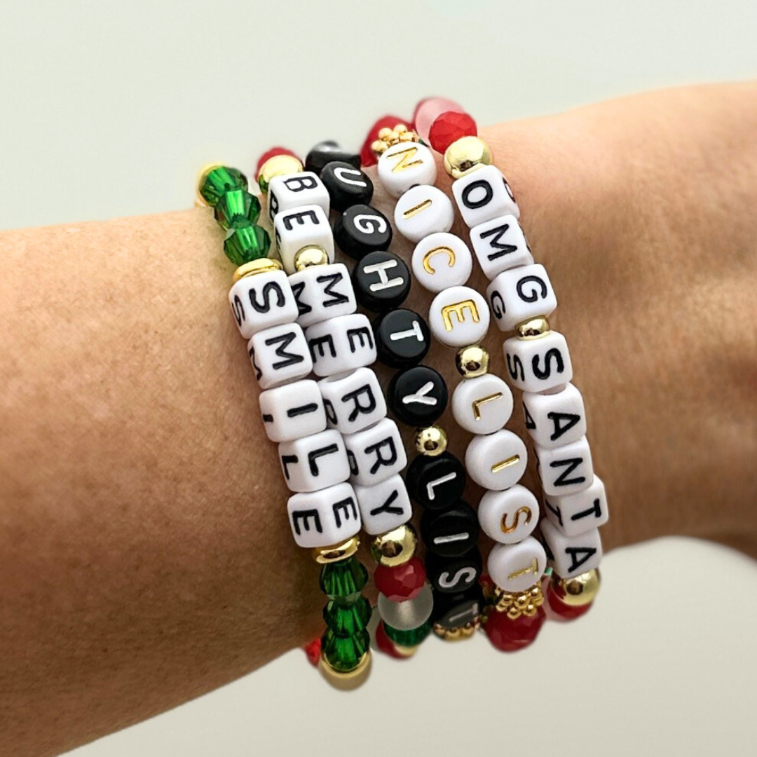 Broadway Stacks CHRISTMAS Collection. 5 stretch bracelets included in Stack. Red, green, white and gold colored beads. Letter beads that spell quotes. Gold star logo bead to remind you that you shine.