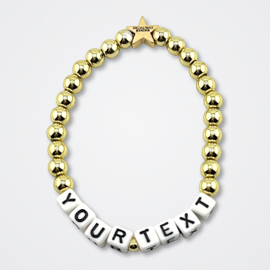 Broadway Stacks elastic stretch bracelets with gold color beads. Letter beads spell out YOUR TEXT, for custom bracelet. Gold star logo bead to remind you that You Shine. Displayed on a gray background.