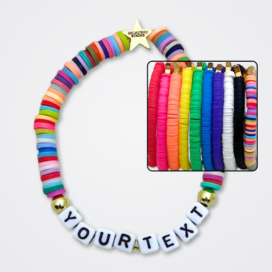 You create your own with CUSTOM text. Broadway Stacks rainbow colors elastic stretch bracelets with gold color accents. Gold star logo bead to remind you that You Shine. Available in 10 colors. Displayed on a gray background.