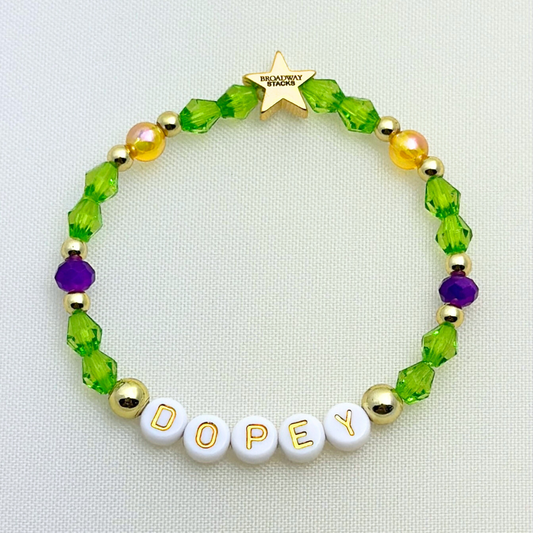 Broadway Stacks Special Edition bracelet. Green, yellow, purple and gold beads. Letter beads that spell Dopey. A portion of the proceeds go to Gilana's Fund. Gold star logo bead to remind you that you shine.